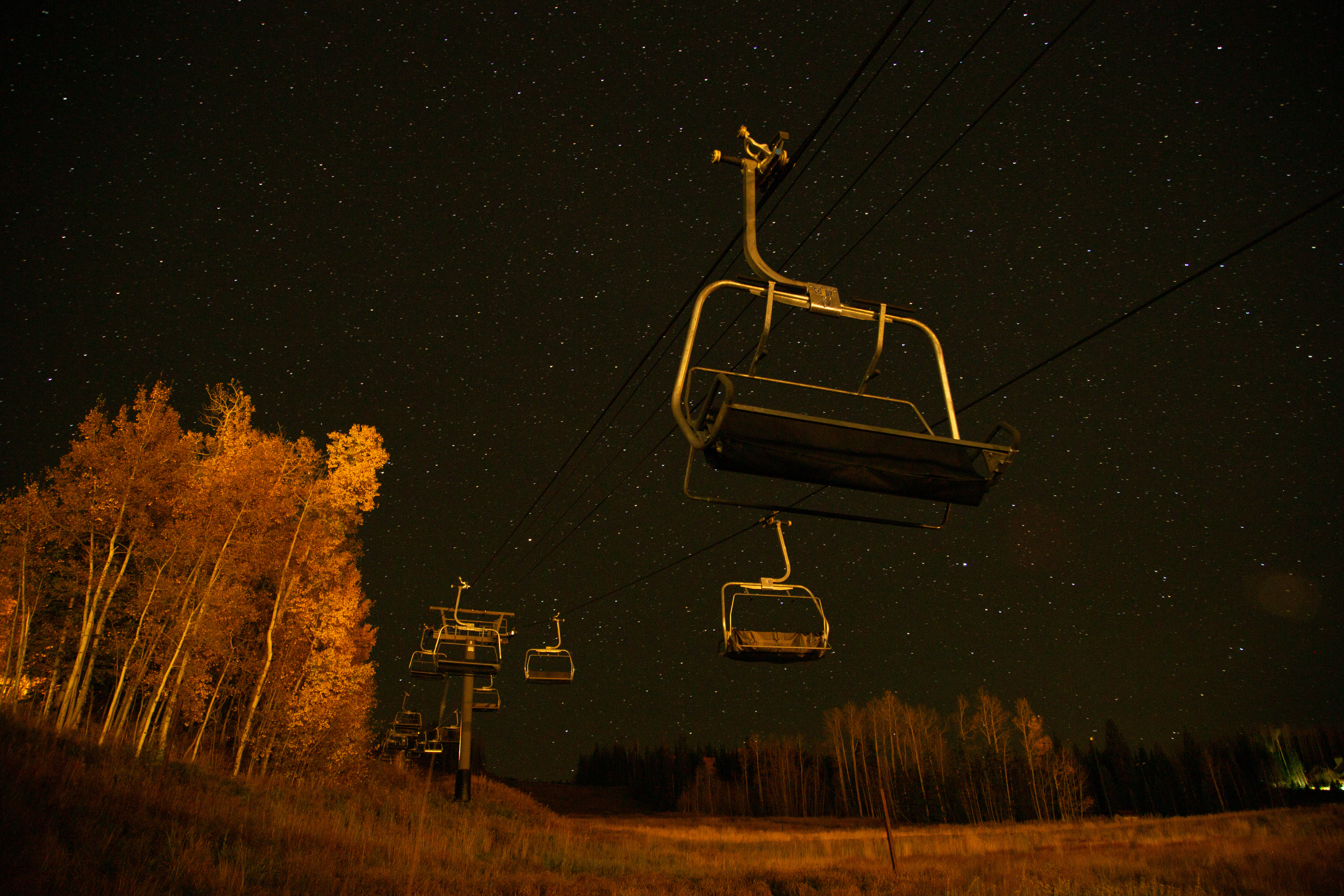 Empty chairlift under a night sky above autumn aspens