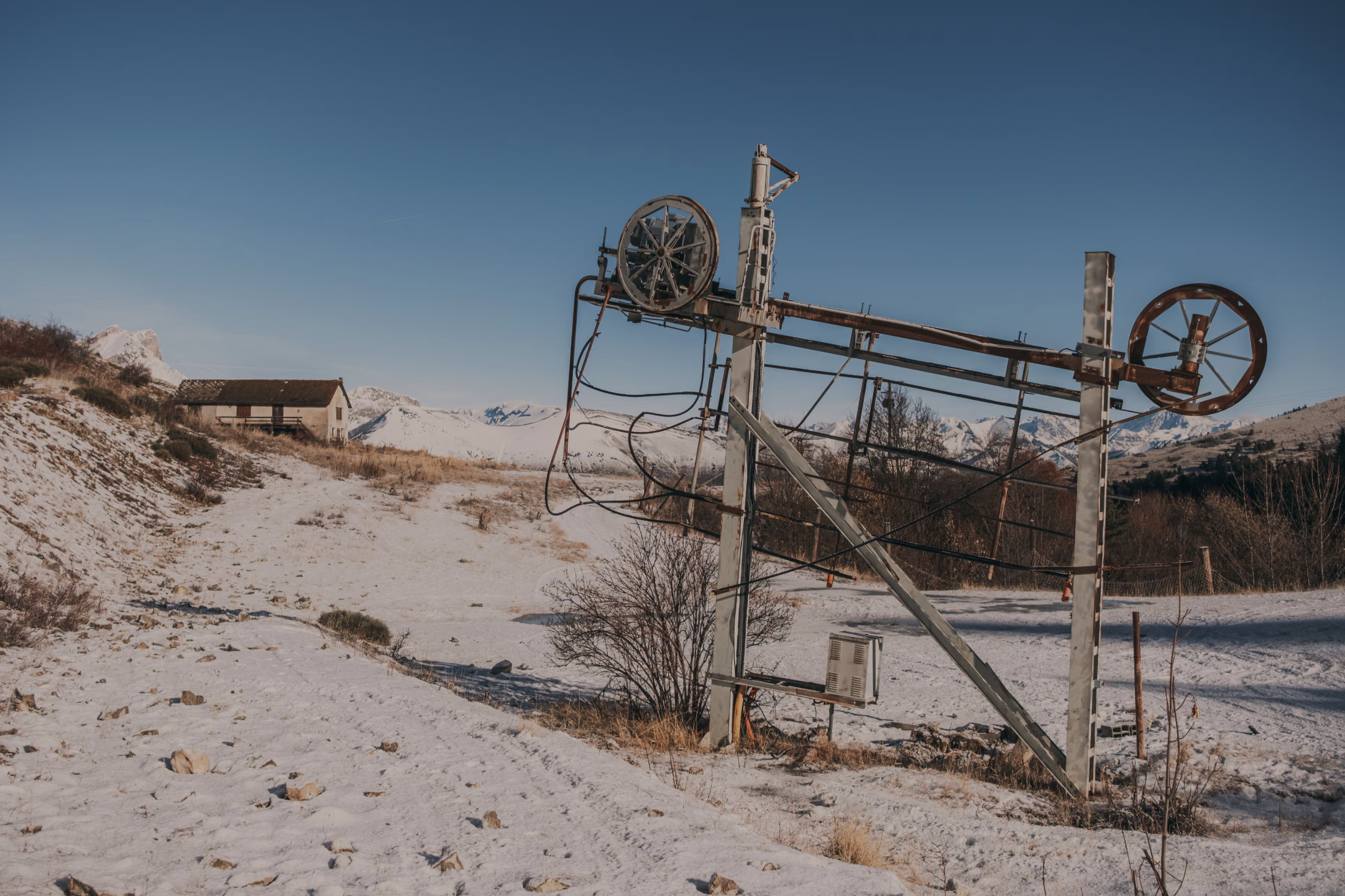 An abandoned drag lift standing on a bare slope in the French Alps
